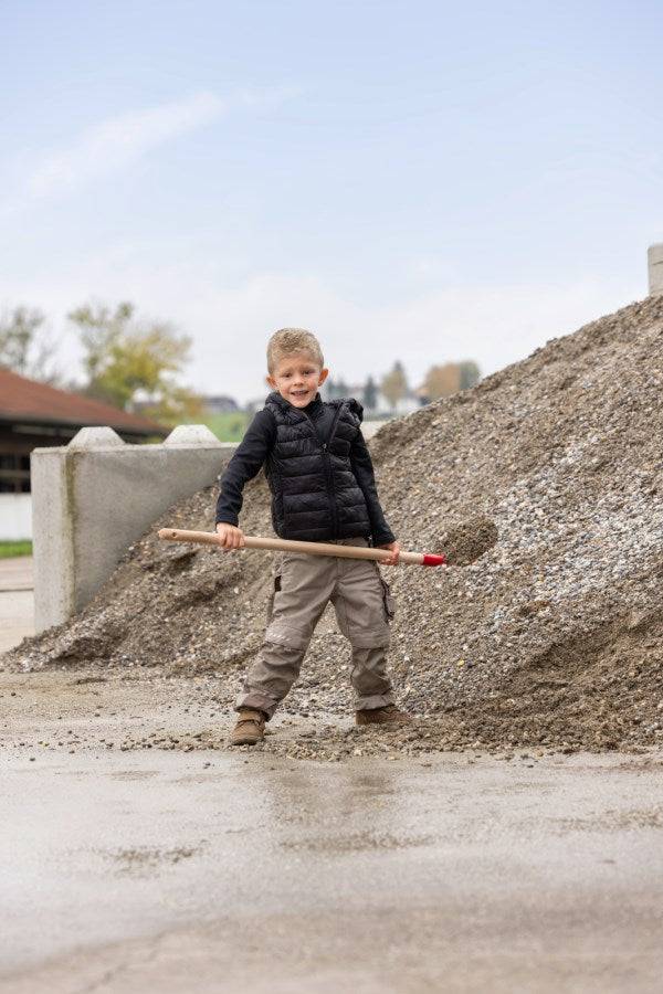 Kind mit Frankfurter Schaufel mit Stiel Mini beim Spielen im Garten, perfekt für kleine Helfer bei Garten- und Bauarbeiten.