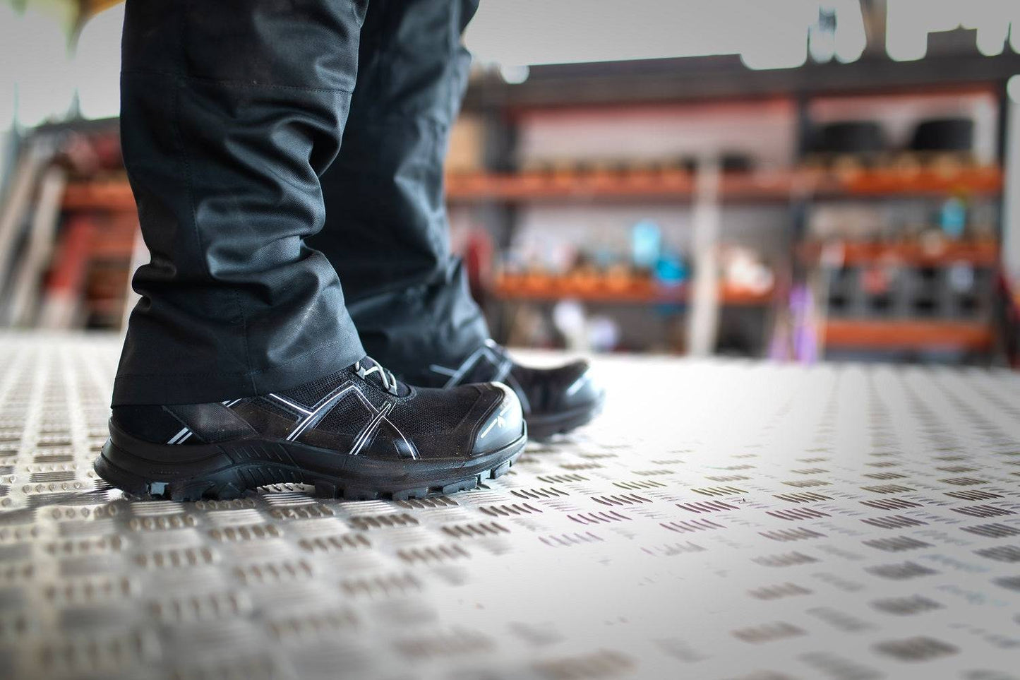 Tragende Black Eagle HAIX Sicherheitsschuhe in Werkstattumgebung, ideal für rutschfeste und leichte Arbeitsschuhe im industriellen Einsatz.