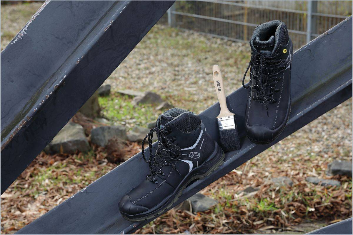 Zwei Paar Sicherheitsschuhe L6122 München von Leibwächter mit durchtrittshemmender Zwischensohle auf Baustellenstahlträgern im Außenbereich platziert.