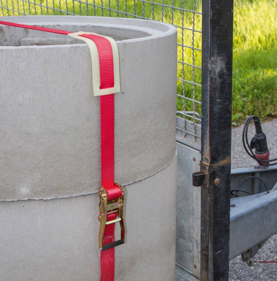 Ratschenzurrgurt mit Spitzhaken 2-teilig 2500kg rot sichert Betonteil auf Anhänger, zuverlässige Lösung für schwere Lasten im Transport.