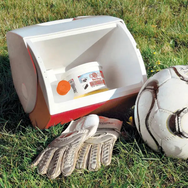 **Alt-Text (Deutsch):**  
Sportmedizin-Set mit Kühlbox, Bandagiercreme, Torwarthandschuhen und Fußball.