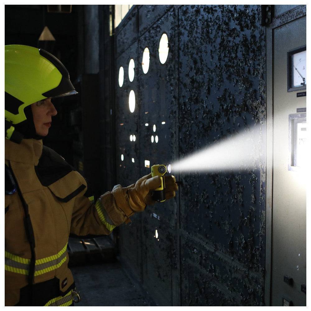 Adalit L-3000 Handleuchte im Einsatz, Feuerwehrmann nutzt die 300 lm LED-Taschenlampe für präzise Beleuchtung in dunkler Umgebung.